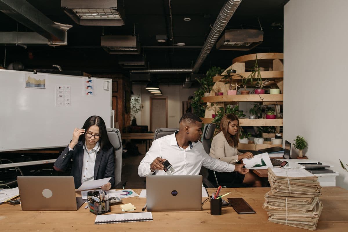 Diverse team collaborating with laptops and documents in a modern office